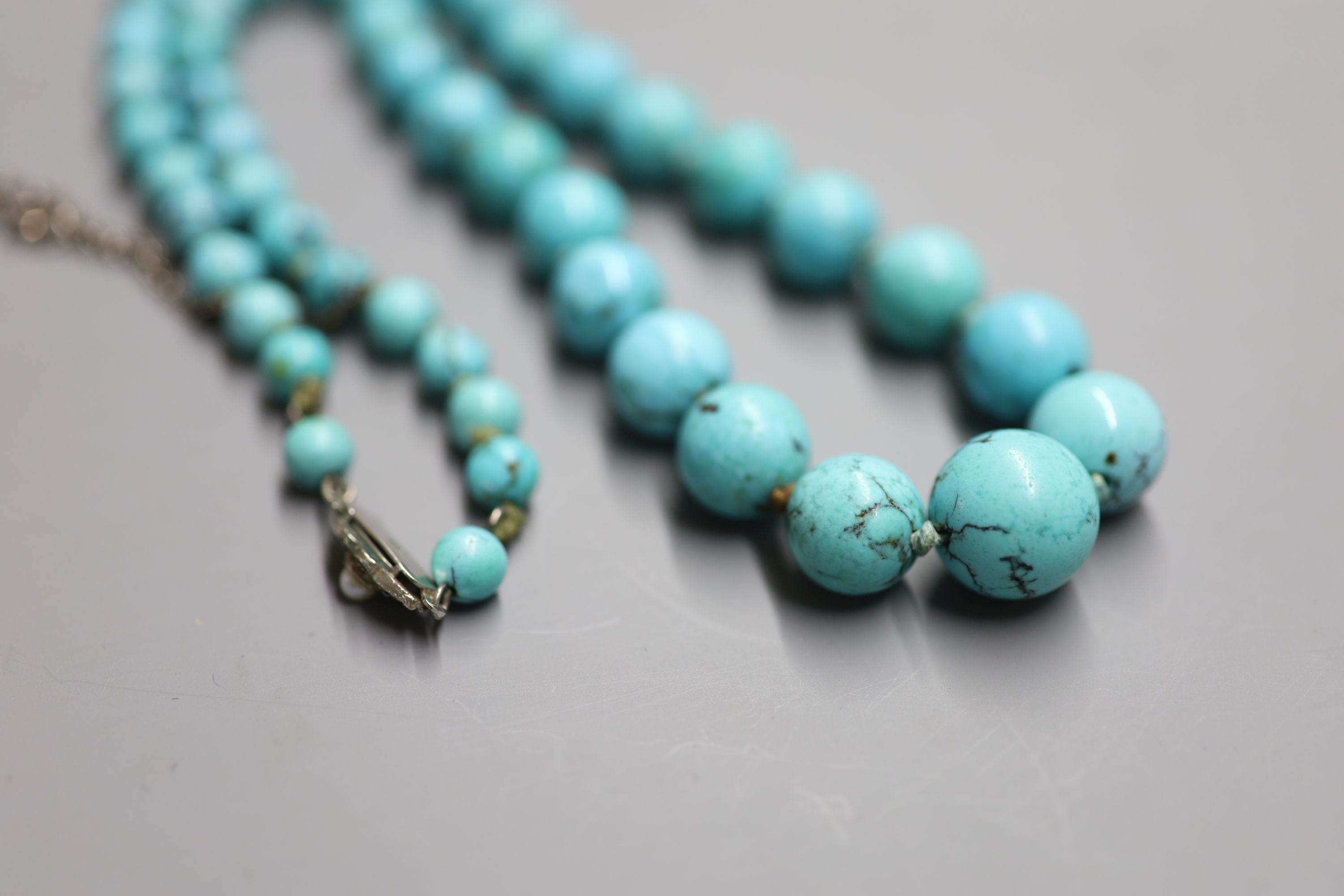 A continental graduated turquoise bead necklace, with marcasite and cultured pearl set white metal clasp, 57cm, gross 73 grams.